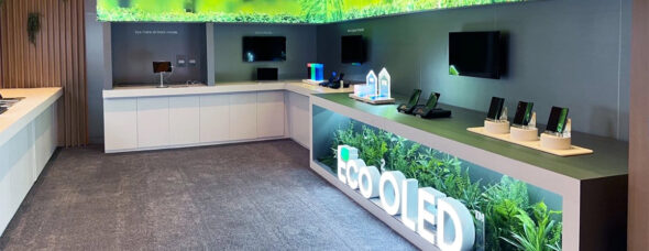 ChatGPT said: Eco OLED trade show booth with green-themed visuals and illuminated signage.