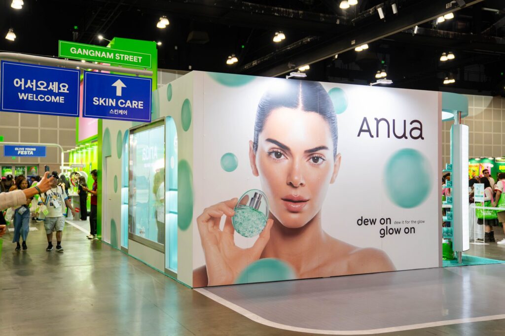 Anua skincare booth with large campaign graphic beneath Gangnam Street signage at Olive Young Festa