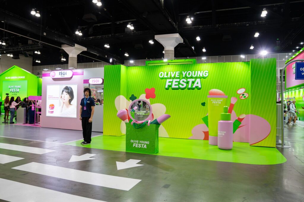 Olive Young Festa green photo wall with oversized product props and floor arrows at KCON LA 2026