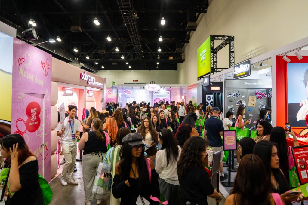 Crowded Hongdae makeup zone with Colorgram booth and pink storefront facades at Olive Young Festa
