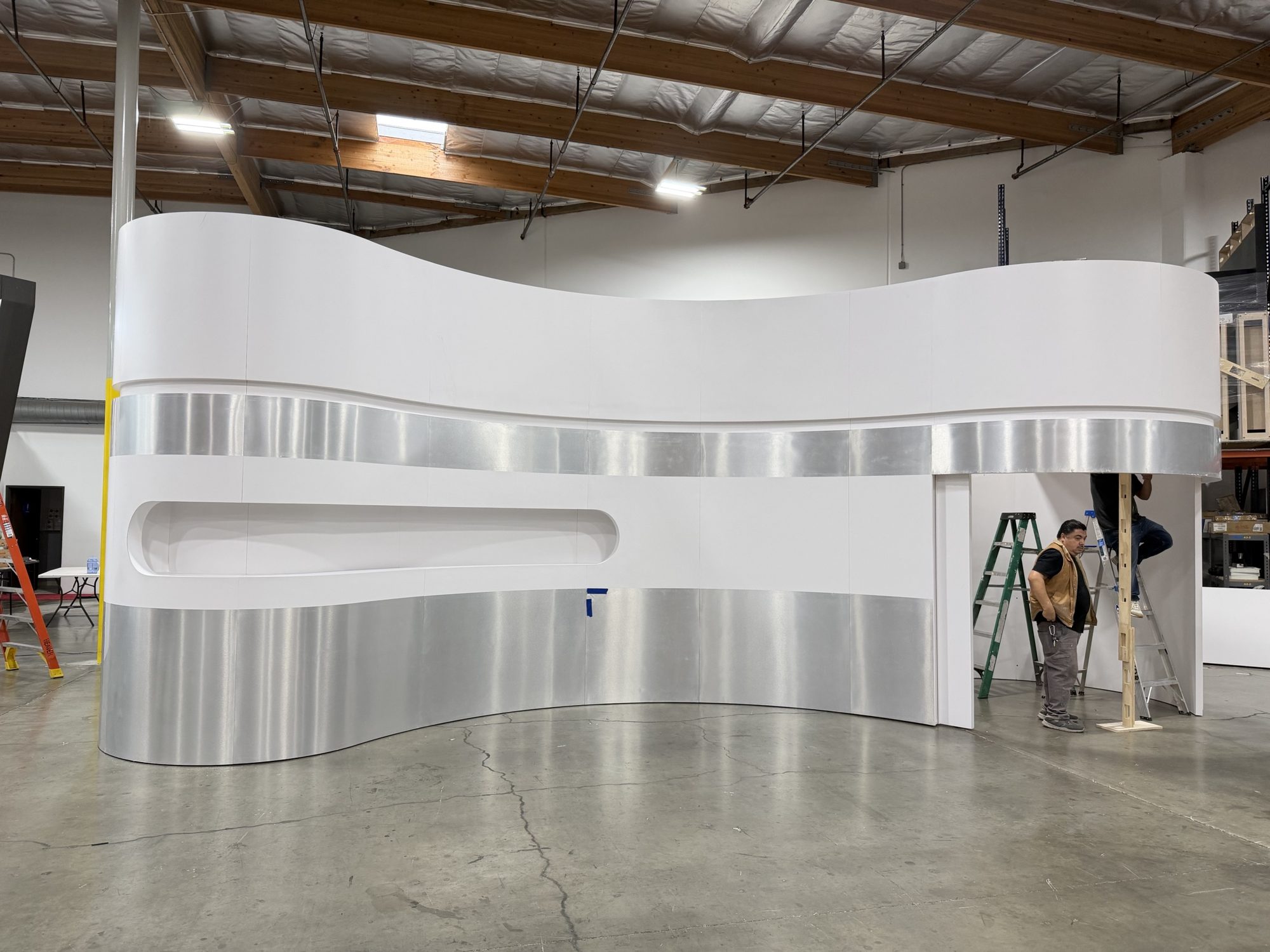 Medicube booth wall finished in white with brushed aluminum bands