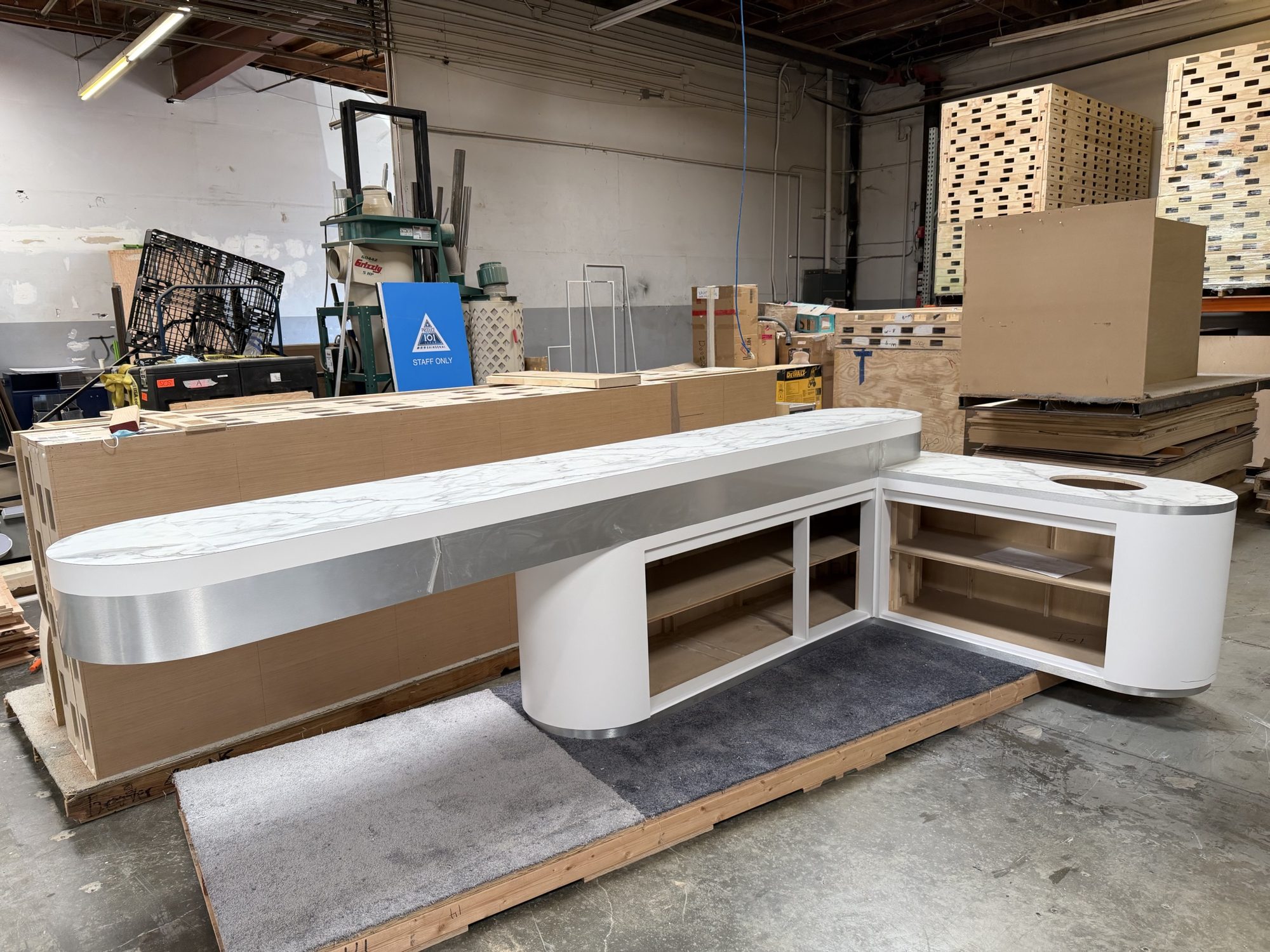 L-shaped product demo counter with marble-look top and open storage