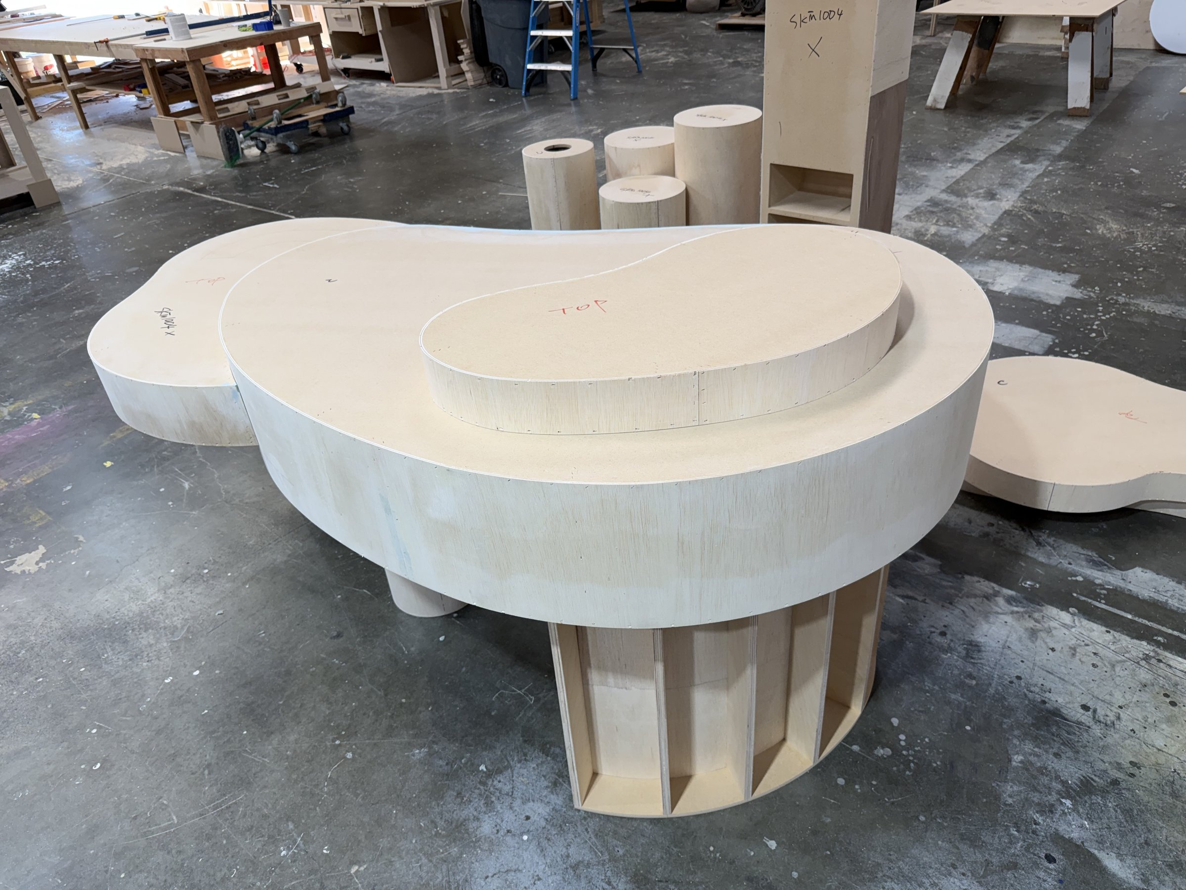 Curved plywood kidney-shaped tables with ribbed internal framing