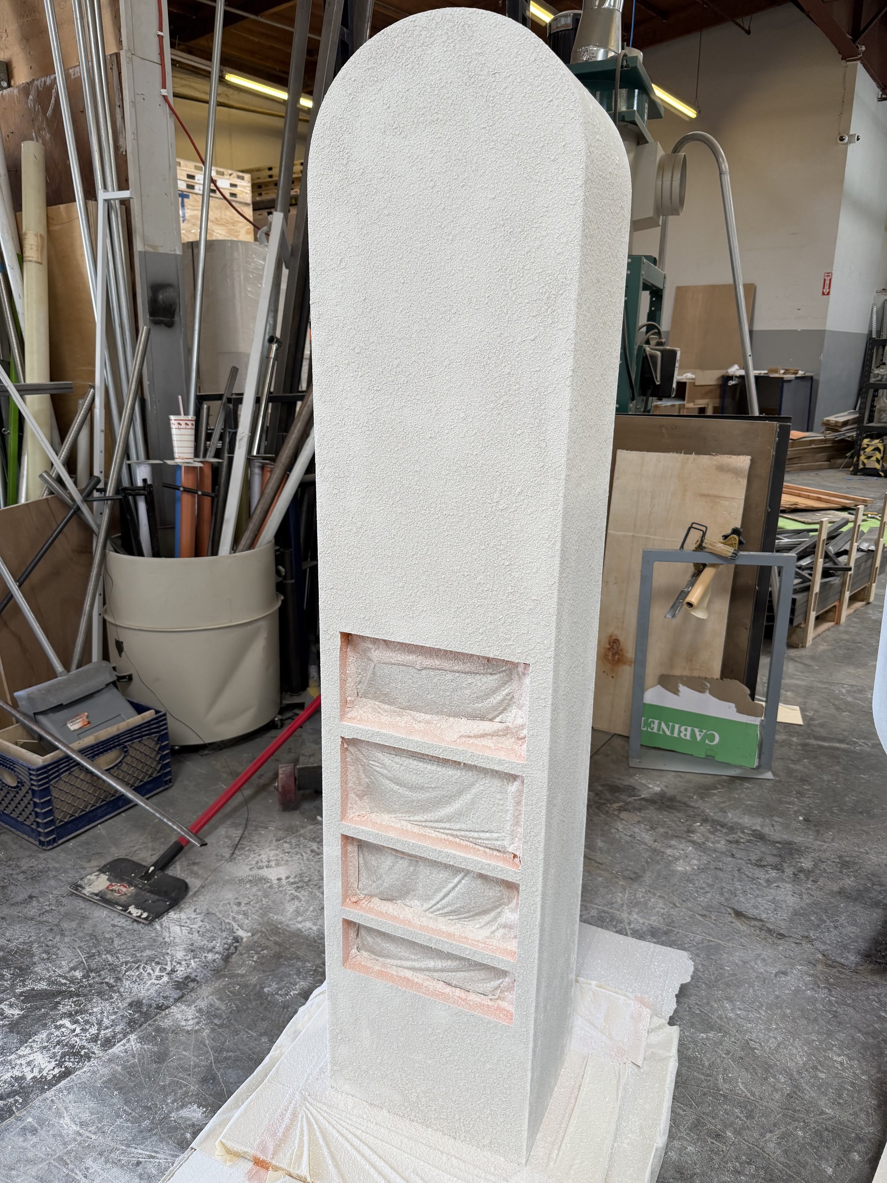 Arched display tower coated in hand-applied stucco, niches masked