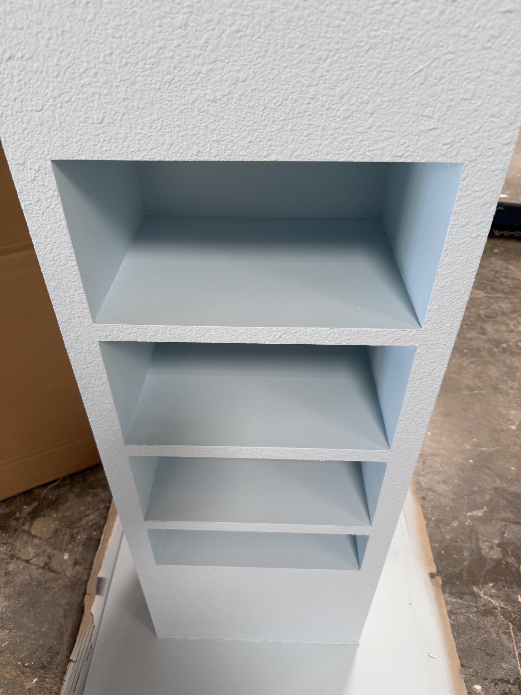 Smooth painted shelf niches inside a textured stucco tower