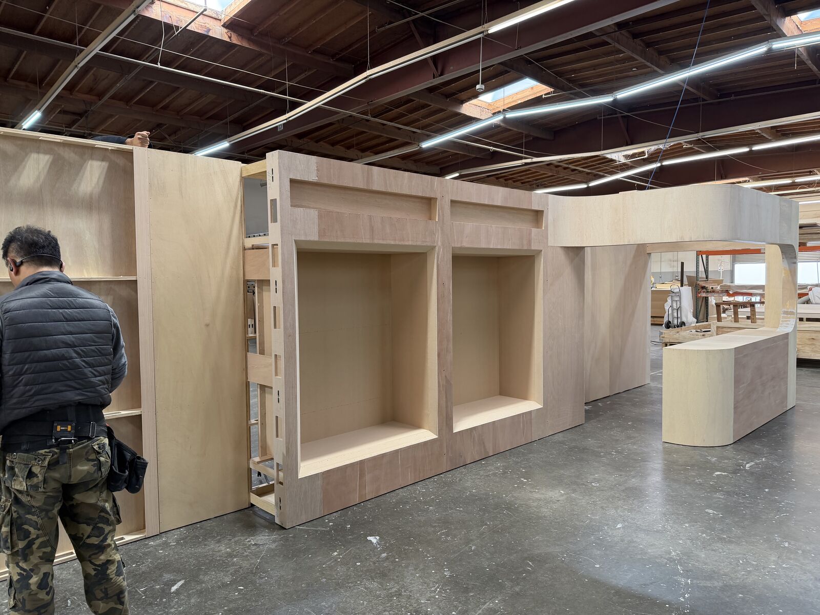 Raw plywood display wall with deep product niches for the Eqqualberry booth in the Beaver XP shop